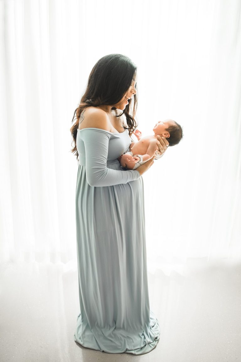 new mom holding her baby while wearing a baby blue dress