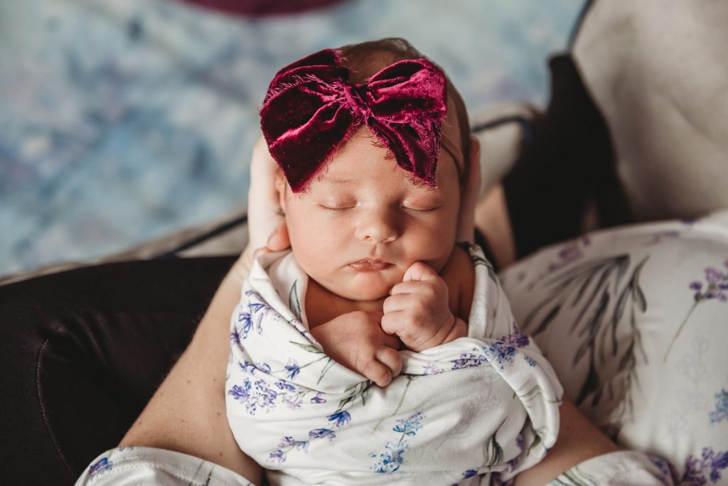 above shot of newborn baby girl with bow