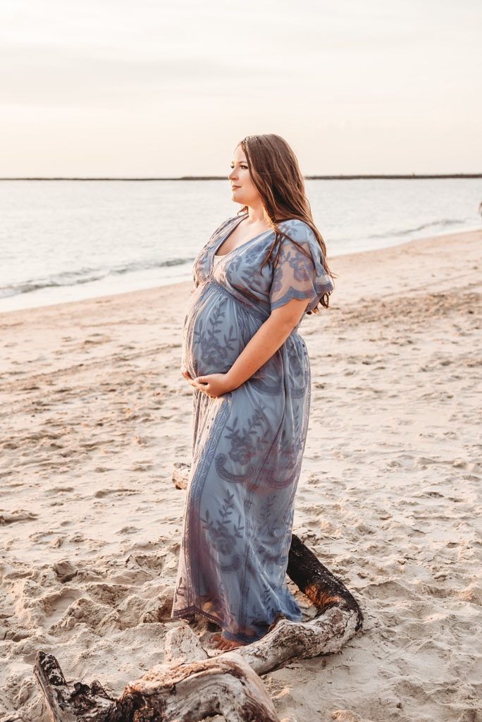 7 month pregnant mom wearing a blue dress at the beach